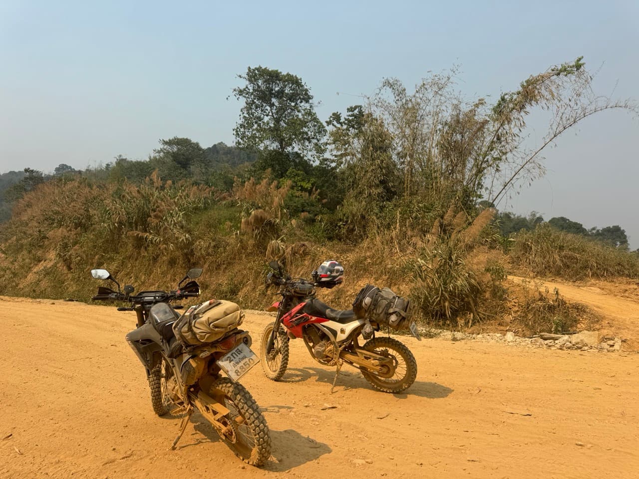 Two Honda CRFs on a red dirt road in karst country between Phonsavan and Vang Vieng, Northern Laos
